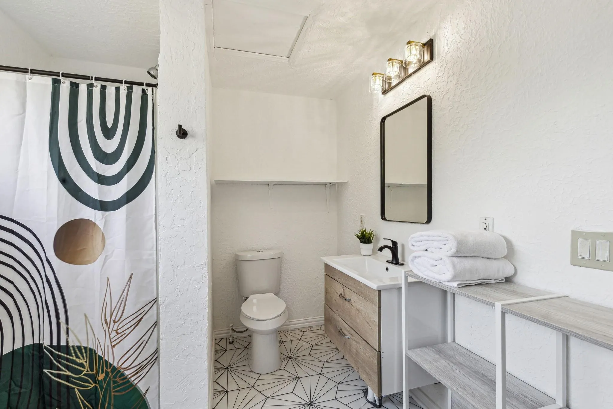 Geometric-patterned floor tiling, modern vanity with integrated sink, sleek rectangular mirror, and contemporary light fixture