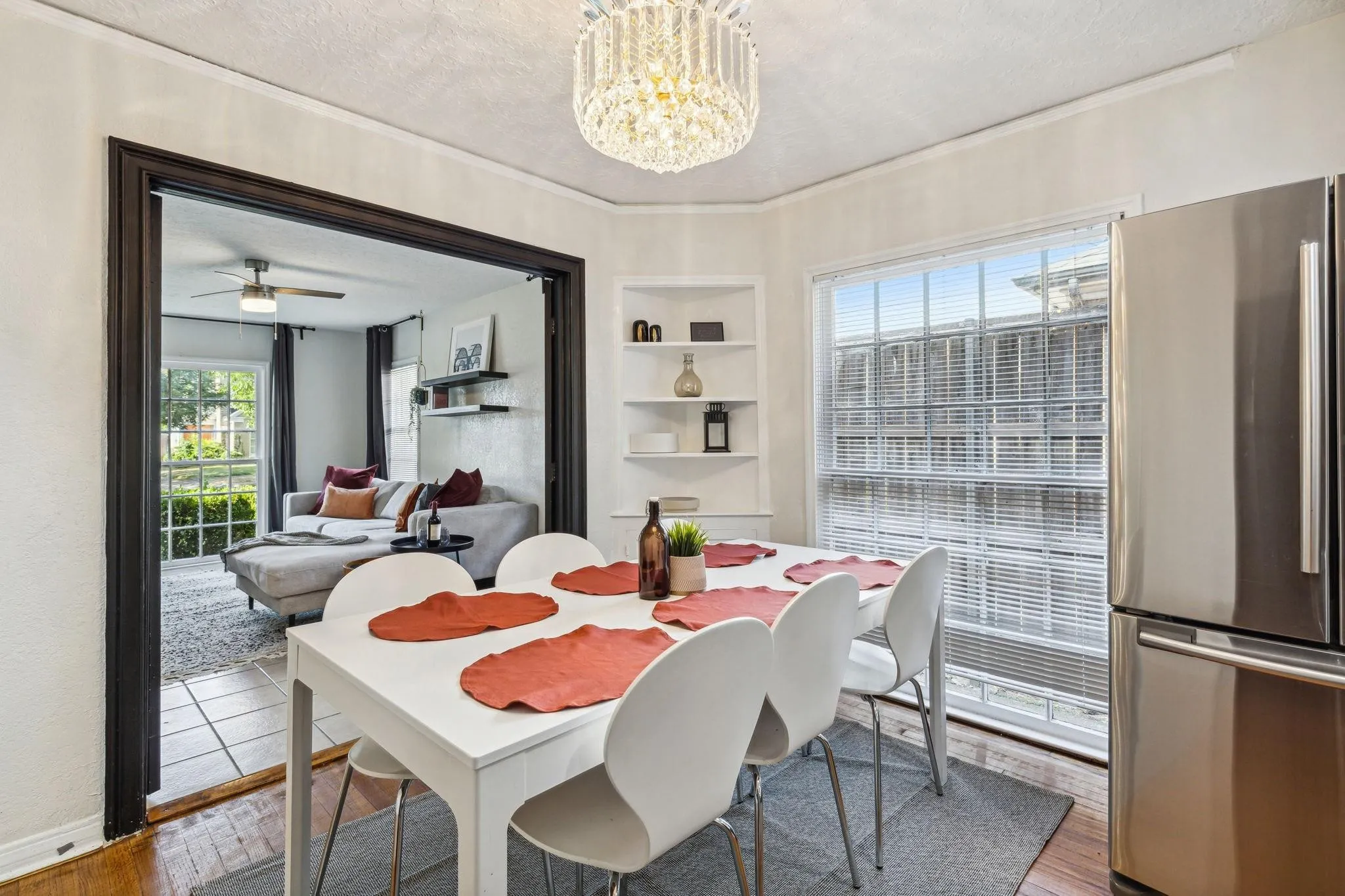 Dining area featuring a crystal chandelier, built-in shelving, stainless steel refrigerator, and a large window with blinds