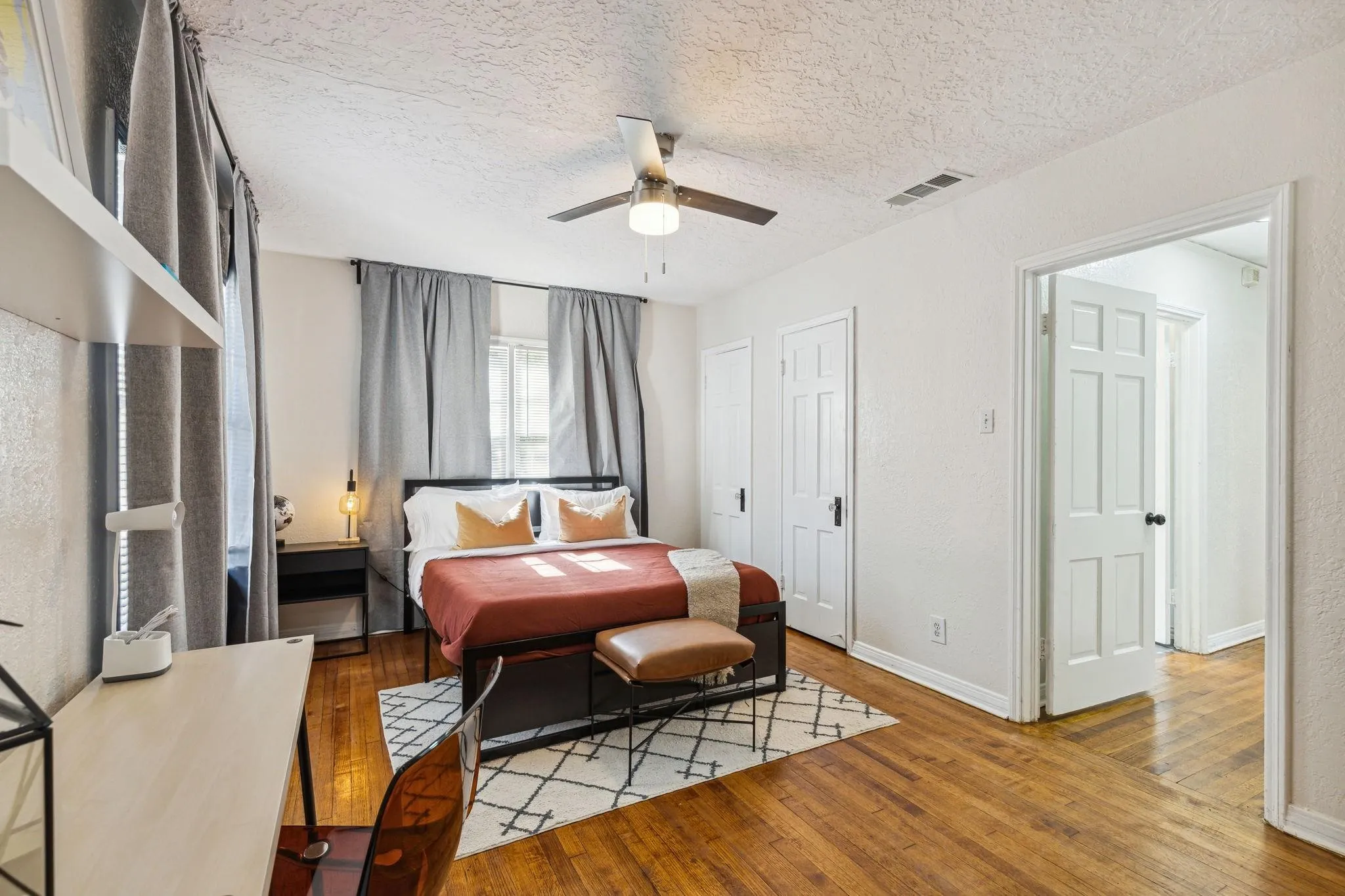Wood-finish flooring, ceiling fan, white paneled doors, and built-in shelving