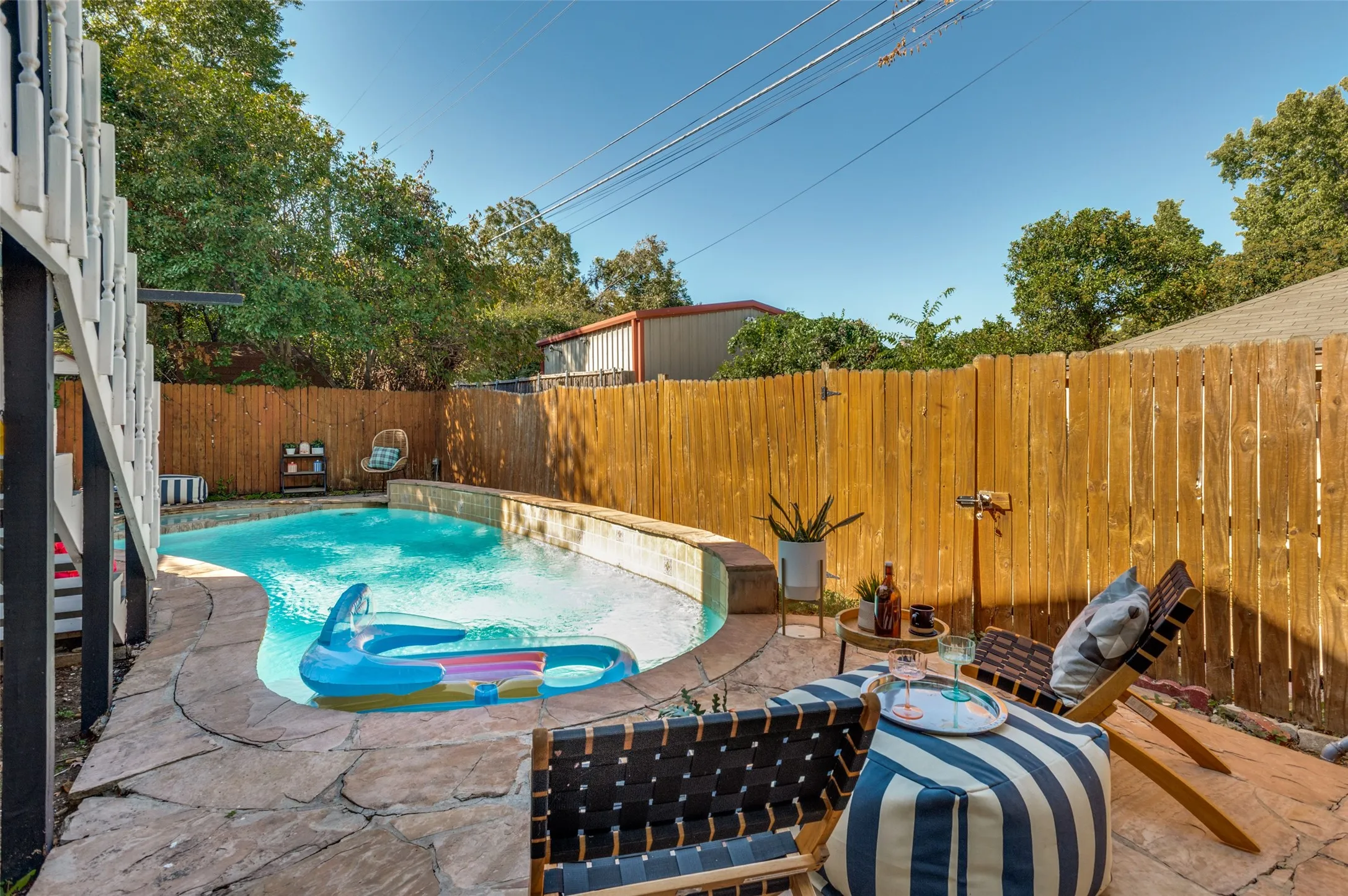 Swimming pool with flagstone patio surround, privacy fencing, and wood-finish balustrade
