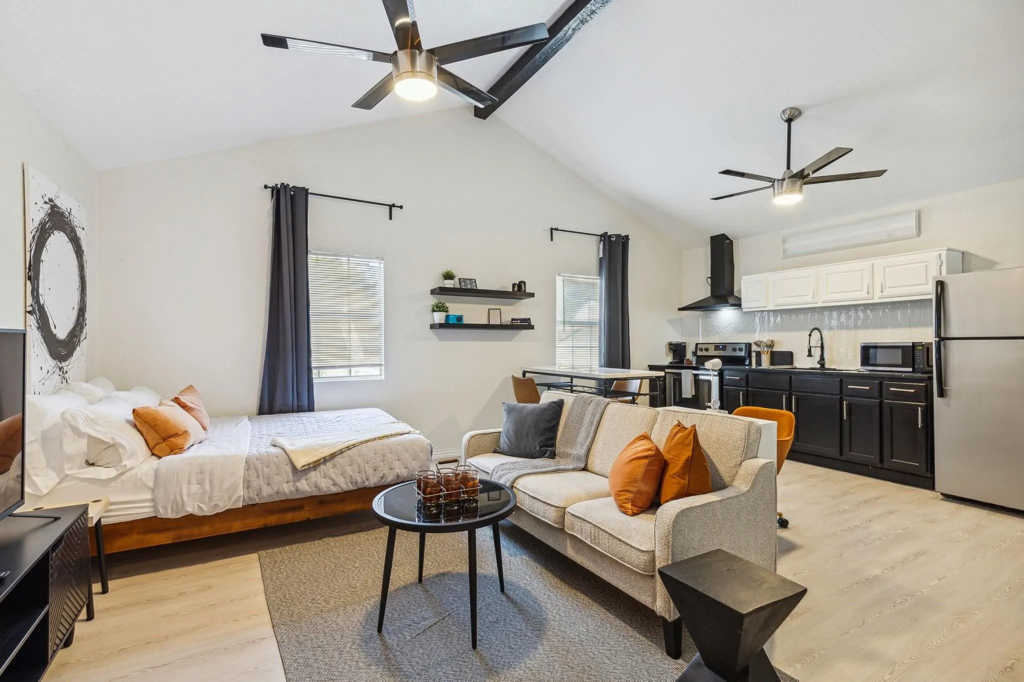 Vaulted ceilings, wood-finish flooring, kitchen with stainless steel appliances, built-in shelving, and two ceiling fans