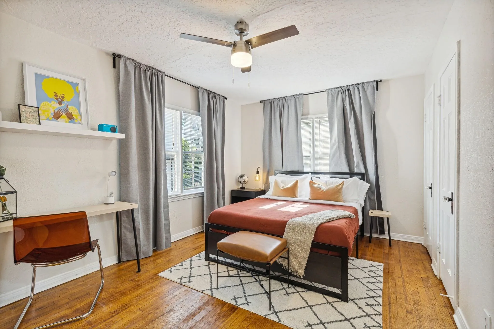 Hardwood flooring, two windows with drapery rods, ceiling fan with integrated lighting, built-in shelving, and a two-panel door