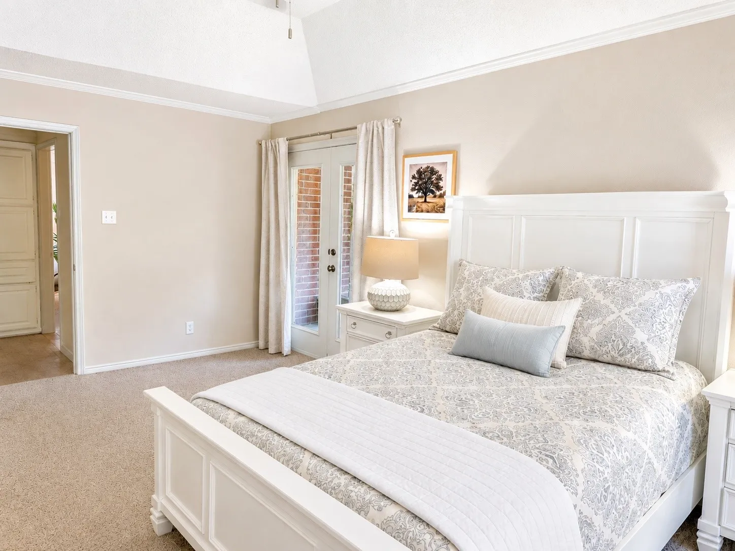 Vaulted ceiling with crown molding, carpeted flooring, and French doors
