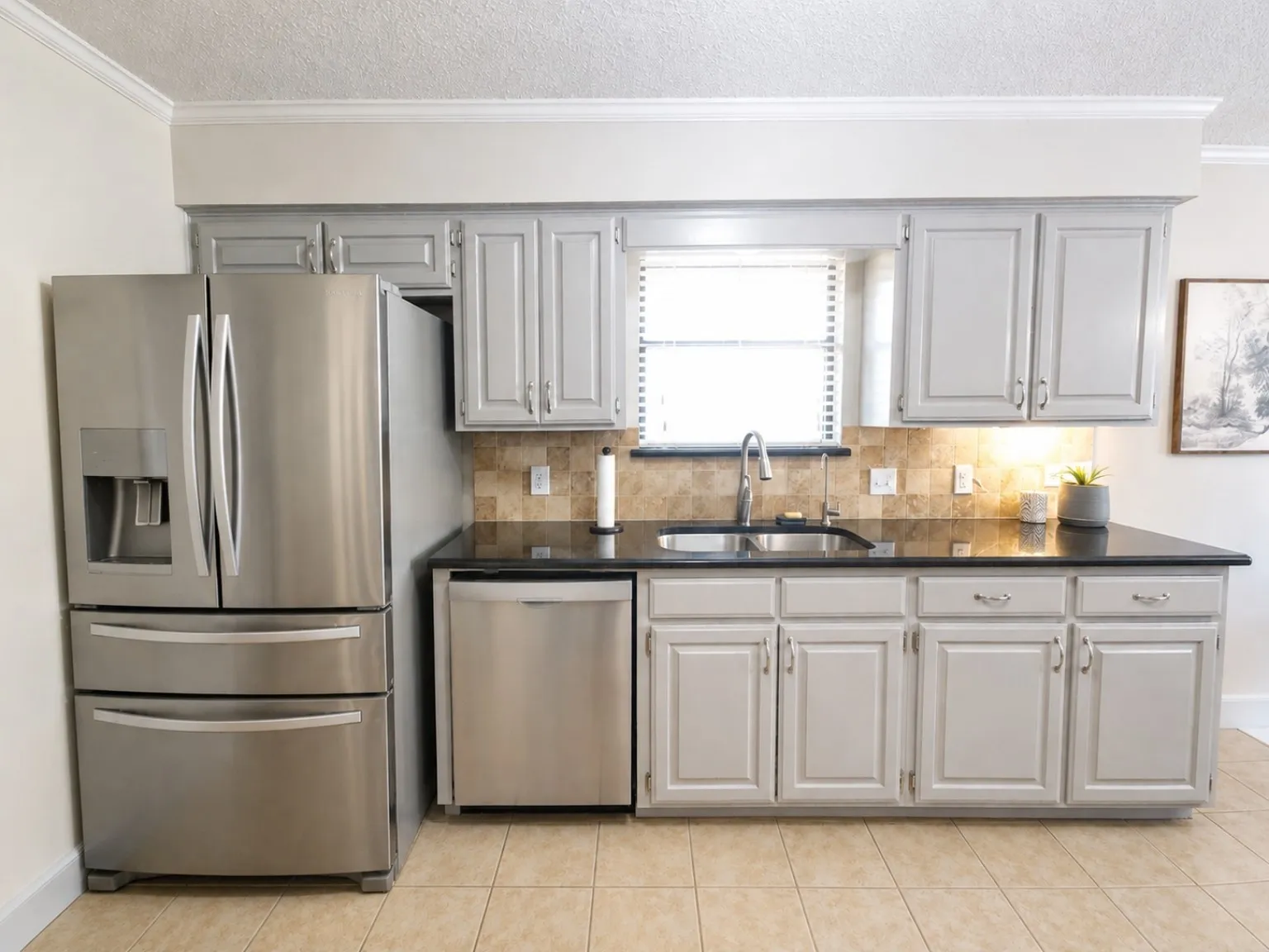 Kitchen featuring light gray cabinetry, dark countertops, tiled backsplash, stainless steel appliances, and a single basin sink with a gooseneck faucet