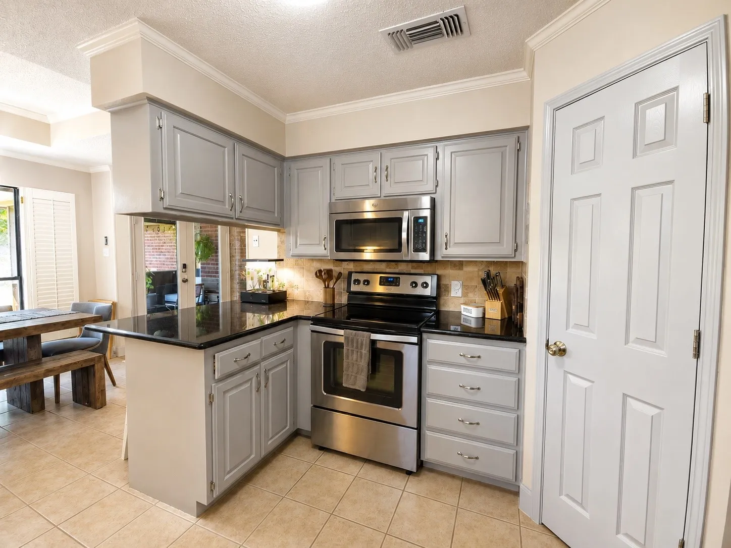 Kitchen featuring tile flooring, gray cabinetry, dark countertops, stainless steel appliances, and a pantry door