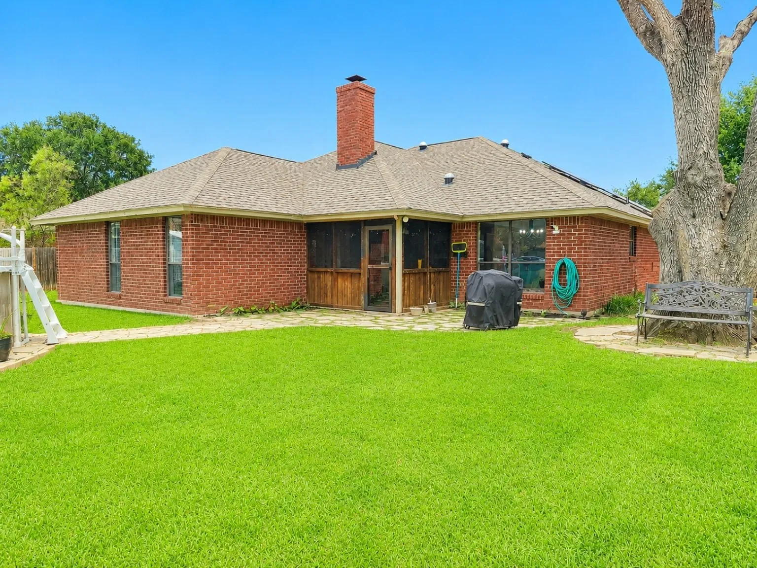 Brick exterior with a screened porch, prominent brick chimney, and a shingle roof