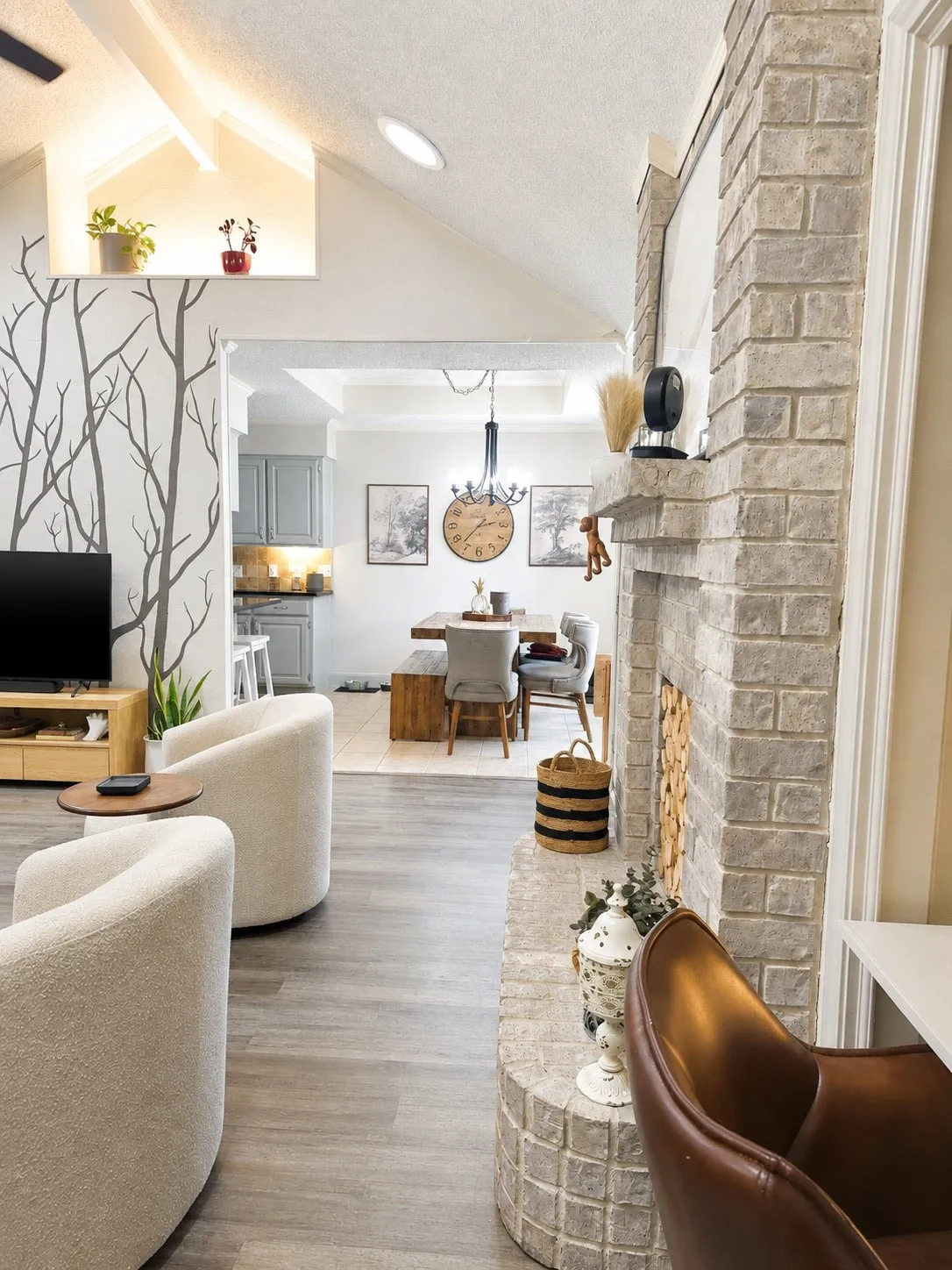 Vaulted ceiling with an illuminated display niche, wood-finish flooring, and a stone fireplace with a raised hearth