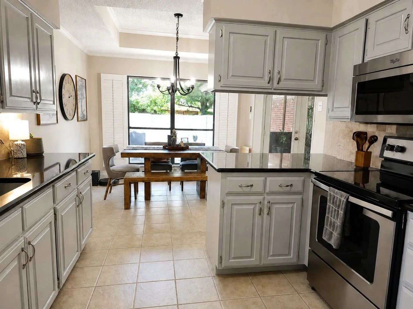 Kitchen featuring light gray cabinetry, dark countertops, a tile backsplash, stainless steel appliances, and tile flooring
