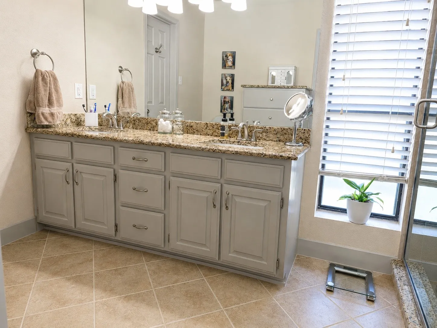 Double vanity with granite countertop, integrated sinks, light gray cabinetry, and tile flooring