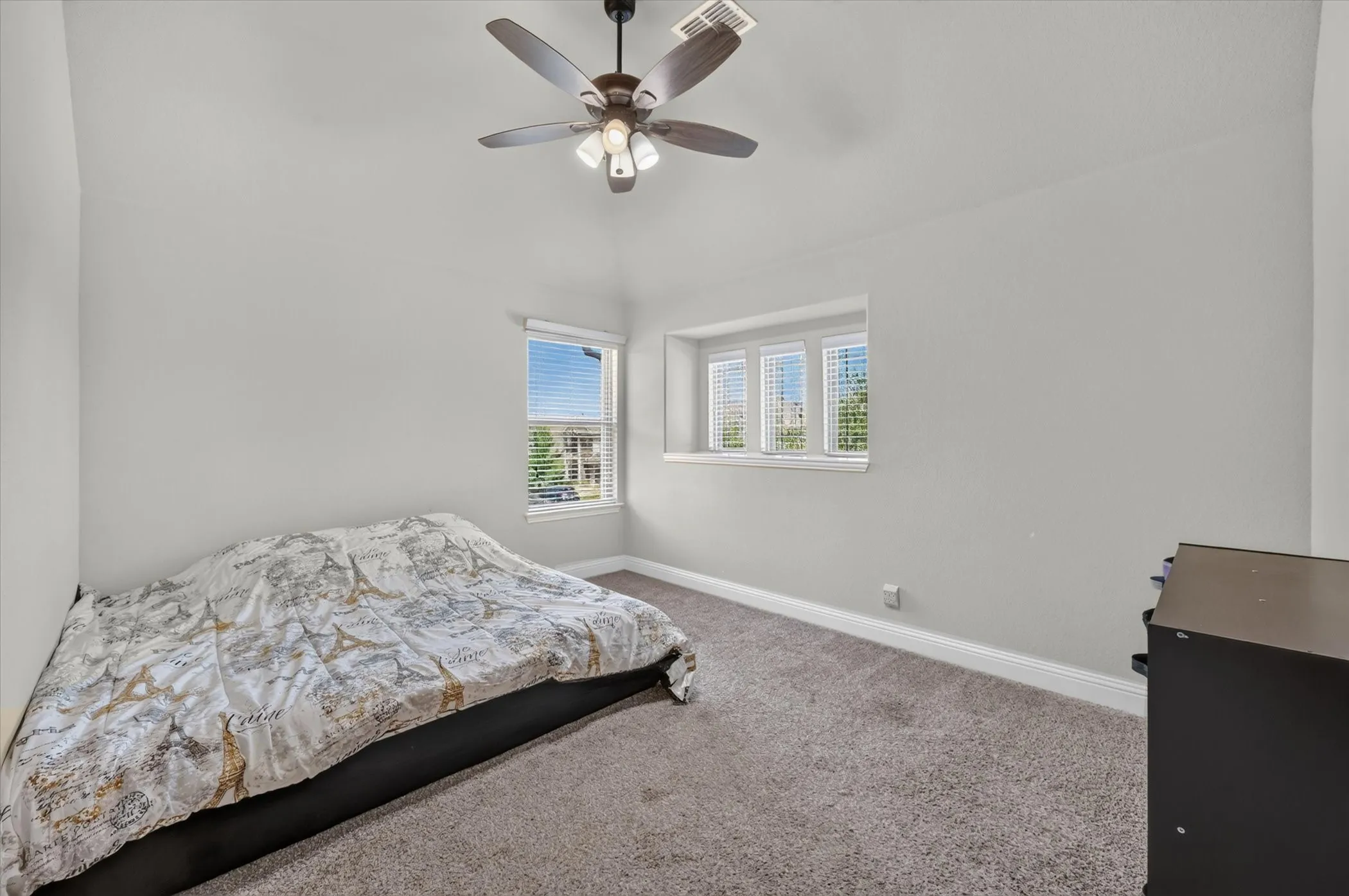 Vaulted ceiling with an attached ceiling fan, carpeted flooring, and multiple windows with blinds