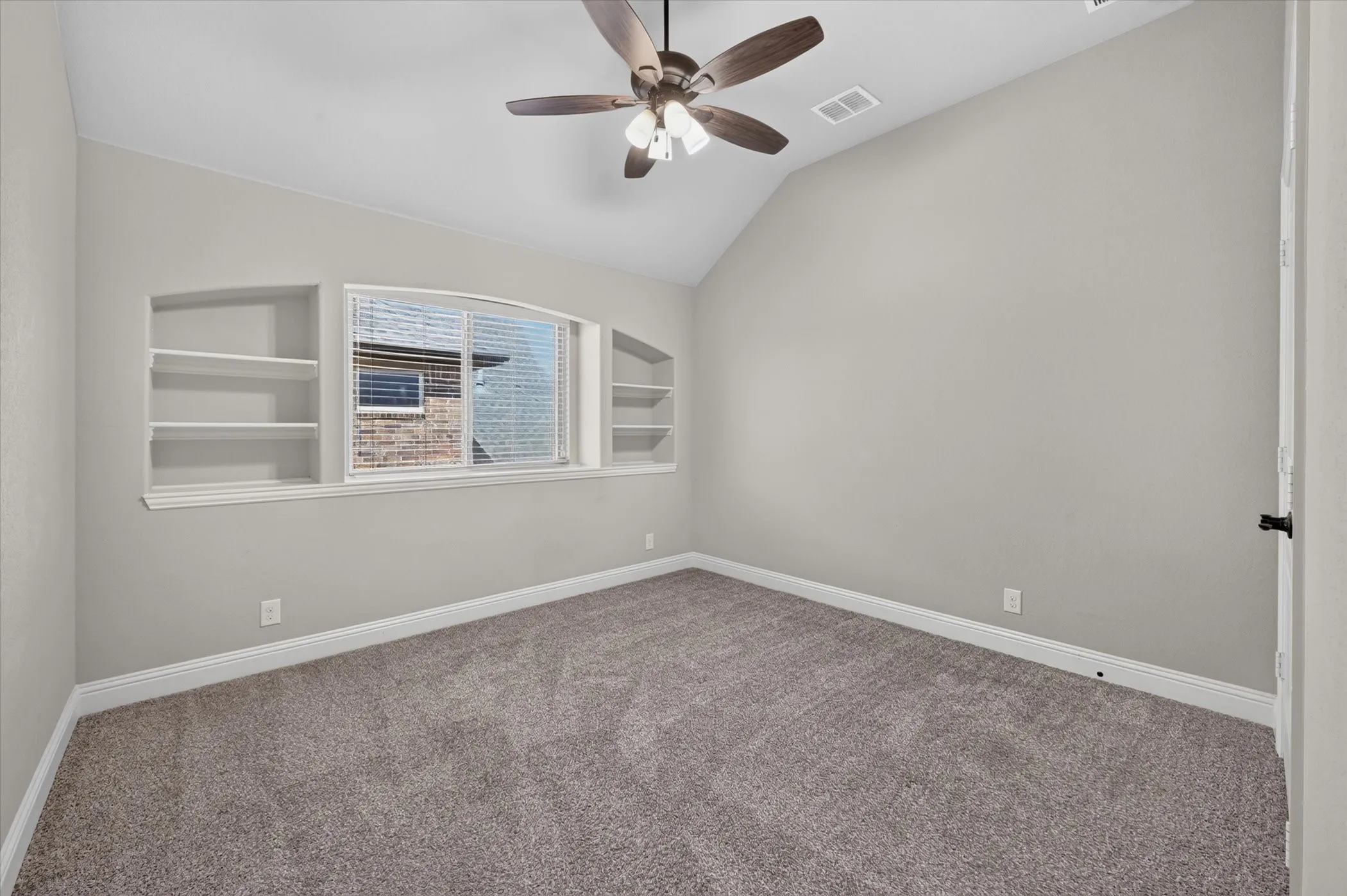 Room with vaulted ceiling, ceiling fan, and built-in shelving