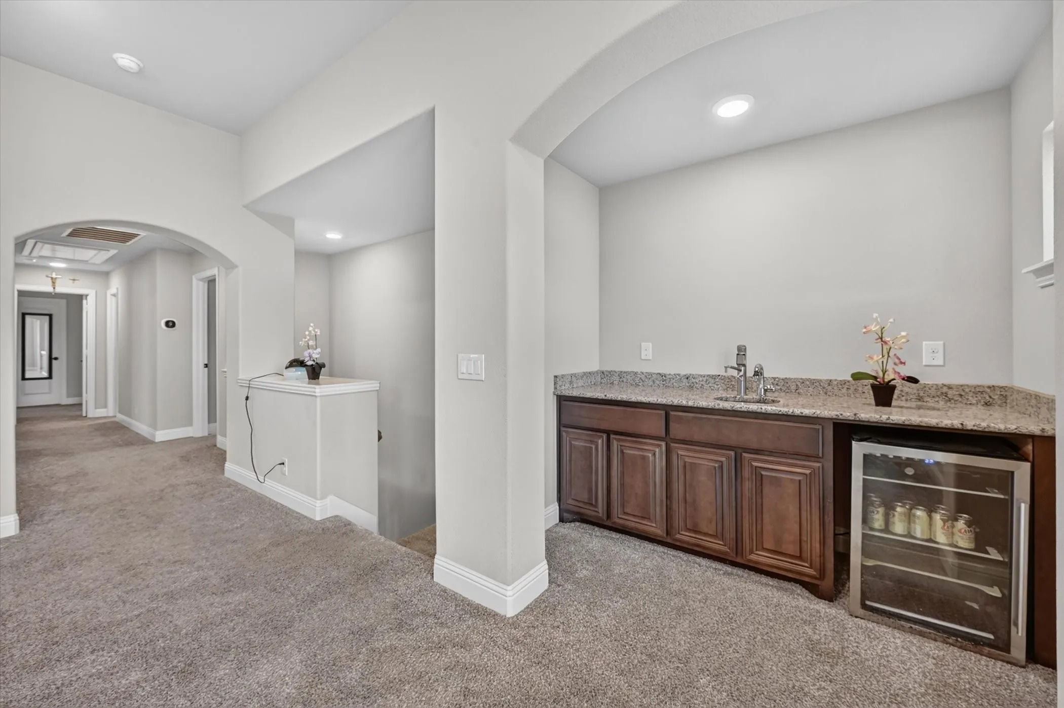 Built-in wet bar featuring dark wood-finish cabinetry, a stainless steel sink, and a granite-style countertop