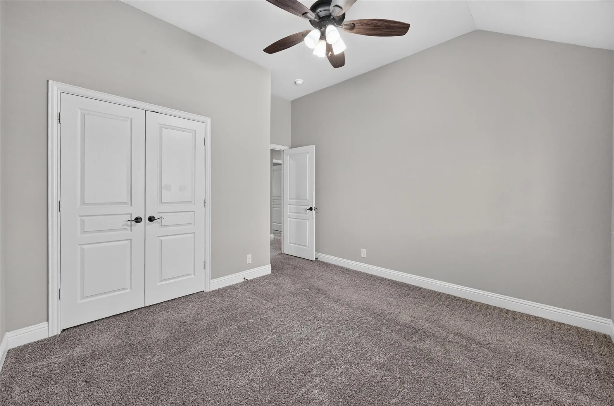 Vaulted ceiling with a ceiling fan, neutral wall tones, and gray carpeting
