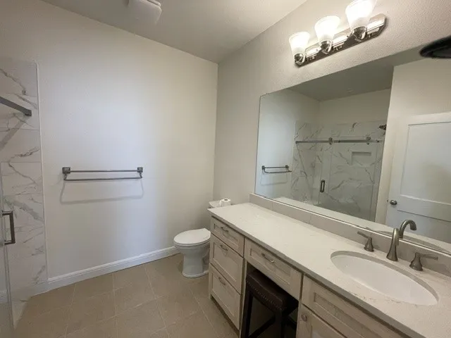 Expansive vanity with integrated sink and chrome faucet, large frameless mirror, and a three-light vanity fixture