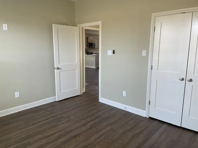 Wood-finish flooring throughout, white trim, and white paneled doors