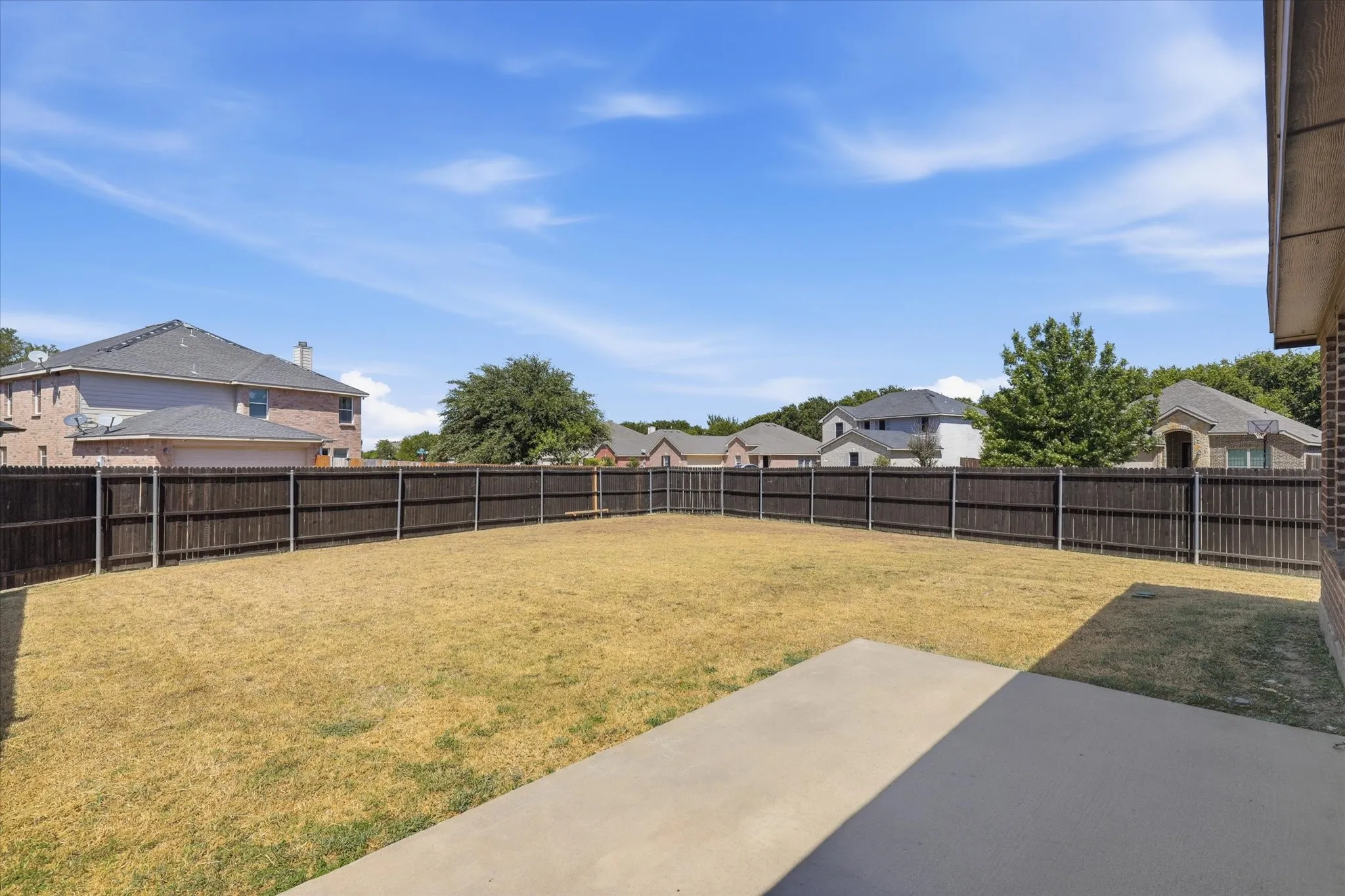 Expansive backyard featuring a privacy fence, concrete patio, and substantial green space