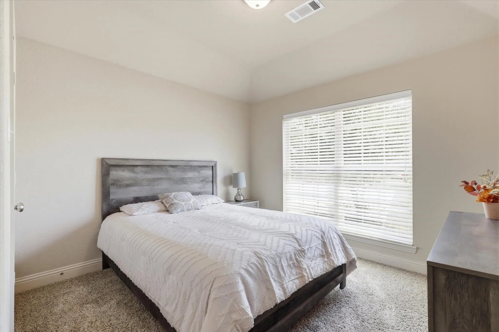 Vaulted ceiling, wall-to-wall carpeting, single window with blinds, recessed ceiling light, and neutral wall tones