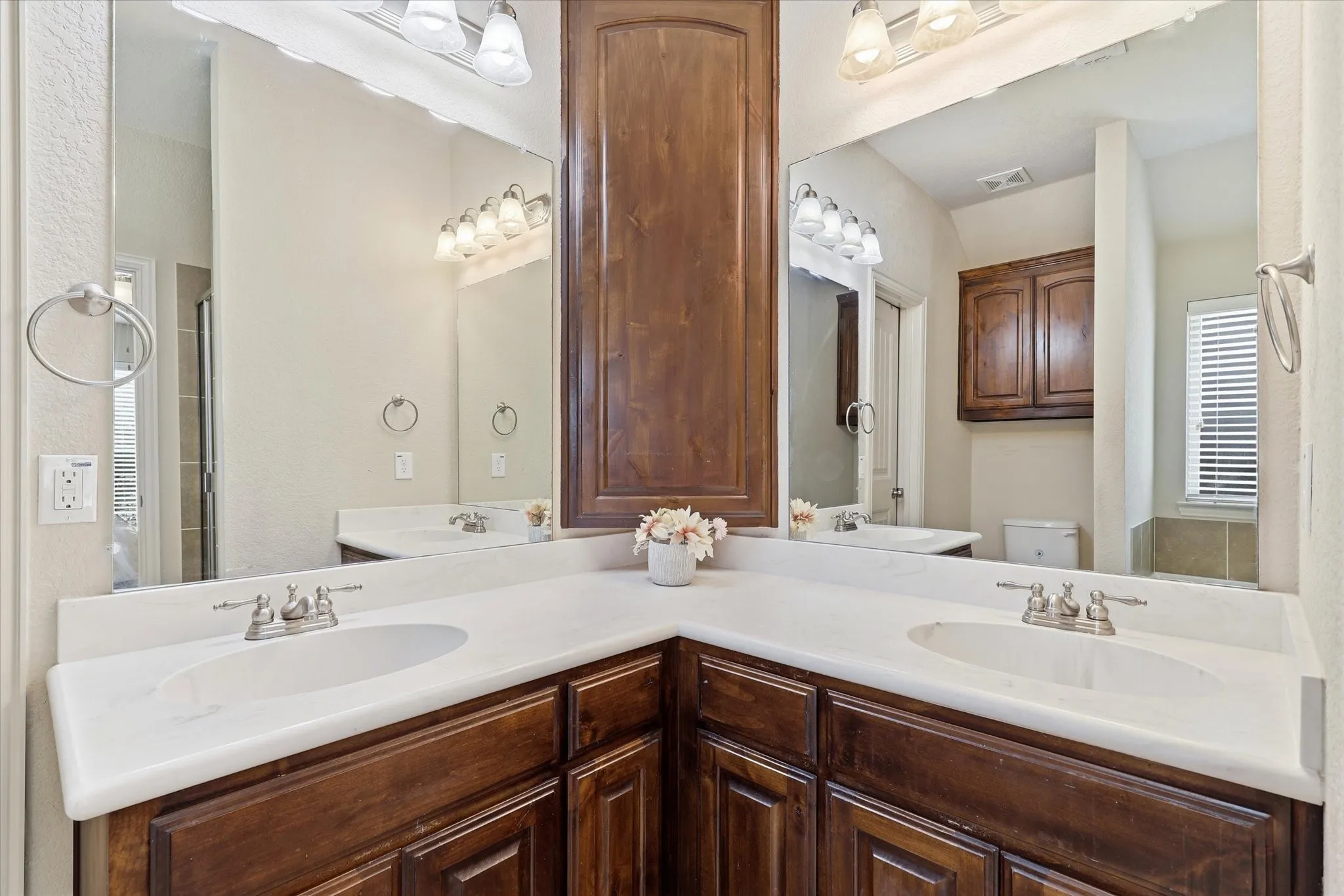 Dual vanities with integrated sinks, rich wood-finish cabinetry, and overhead vanity lighting