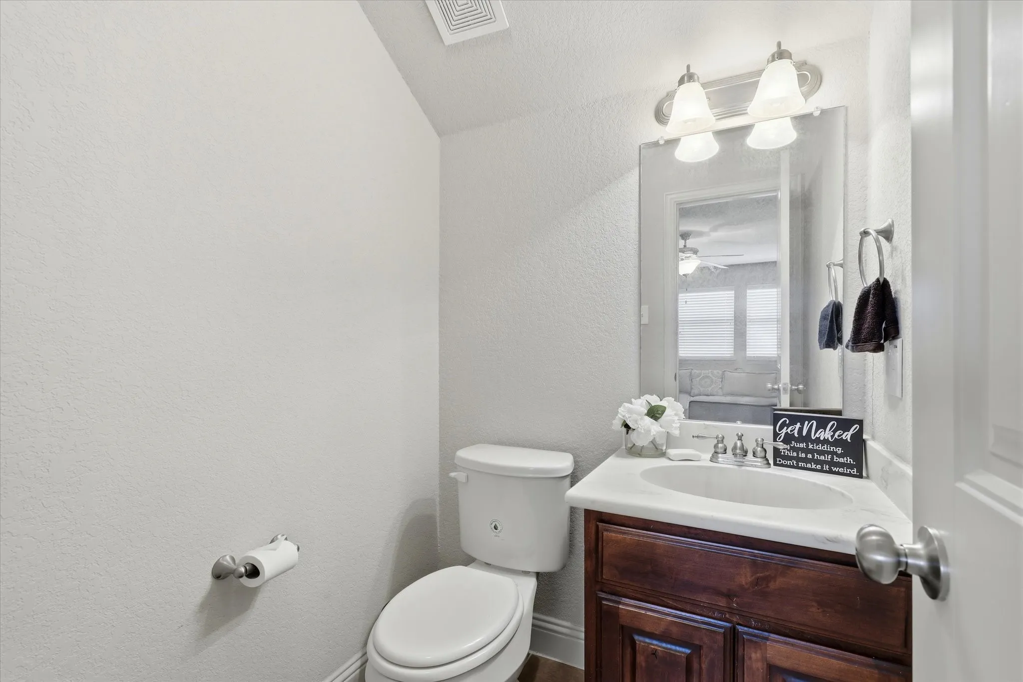 Bathroom featuring a wood-finish vanity with an integrated sink and a wall-mounted mirror