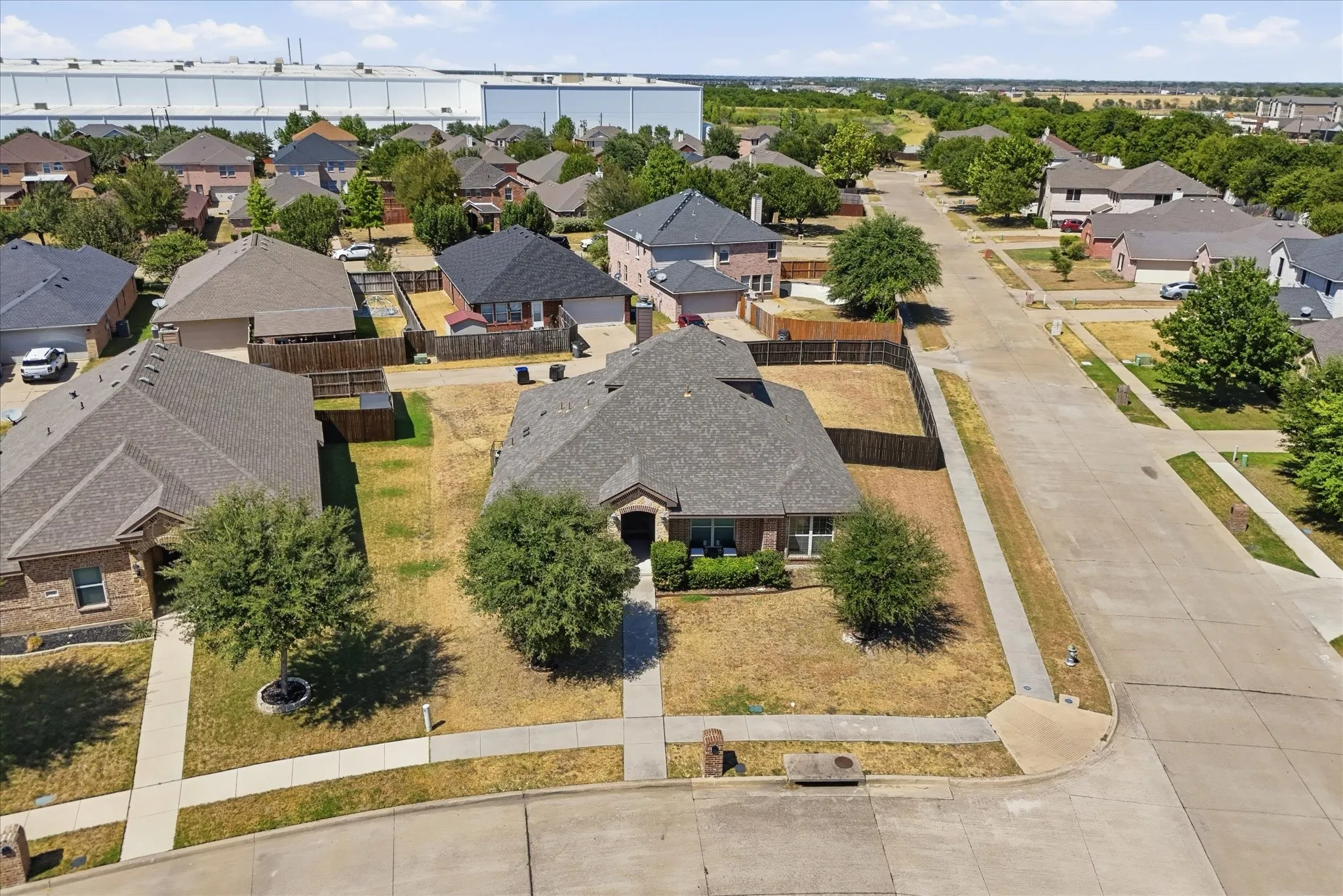 Brick facade residence with a gabled roof, established front yard trees, and a concrete driveway