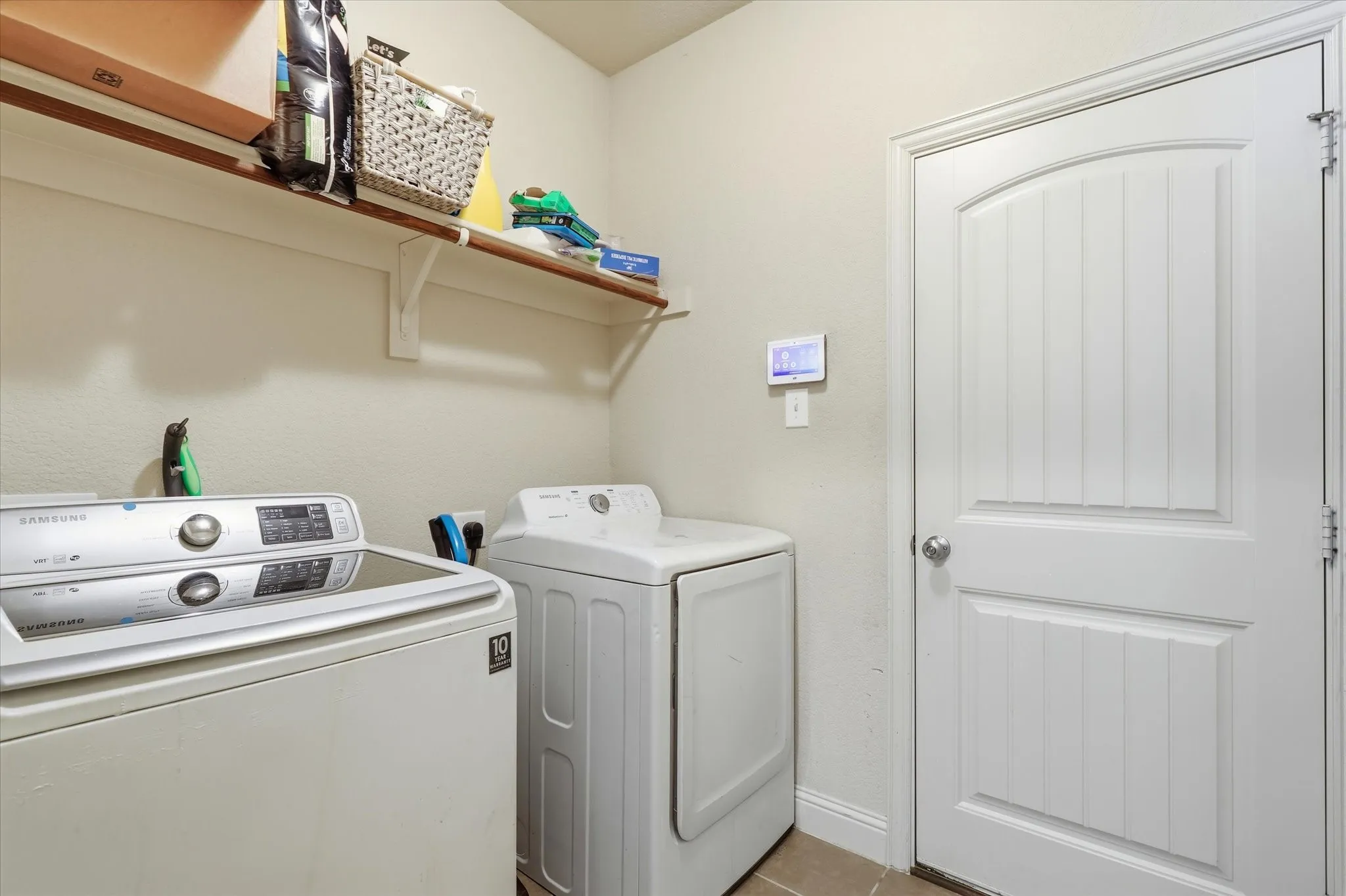Built-in shelving with hanging rod, durable tile flooring, and a paneled interior door with arched detail