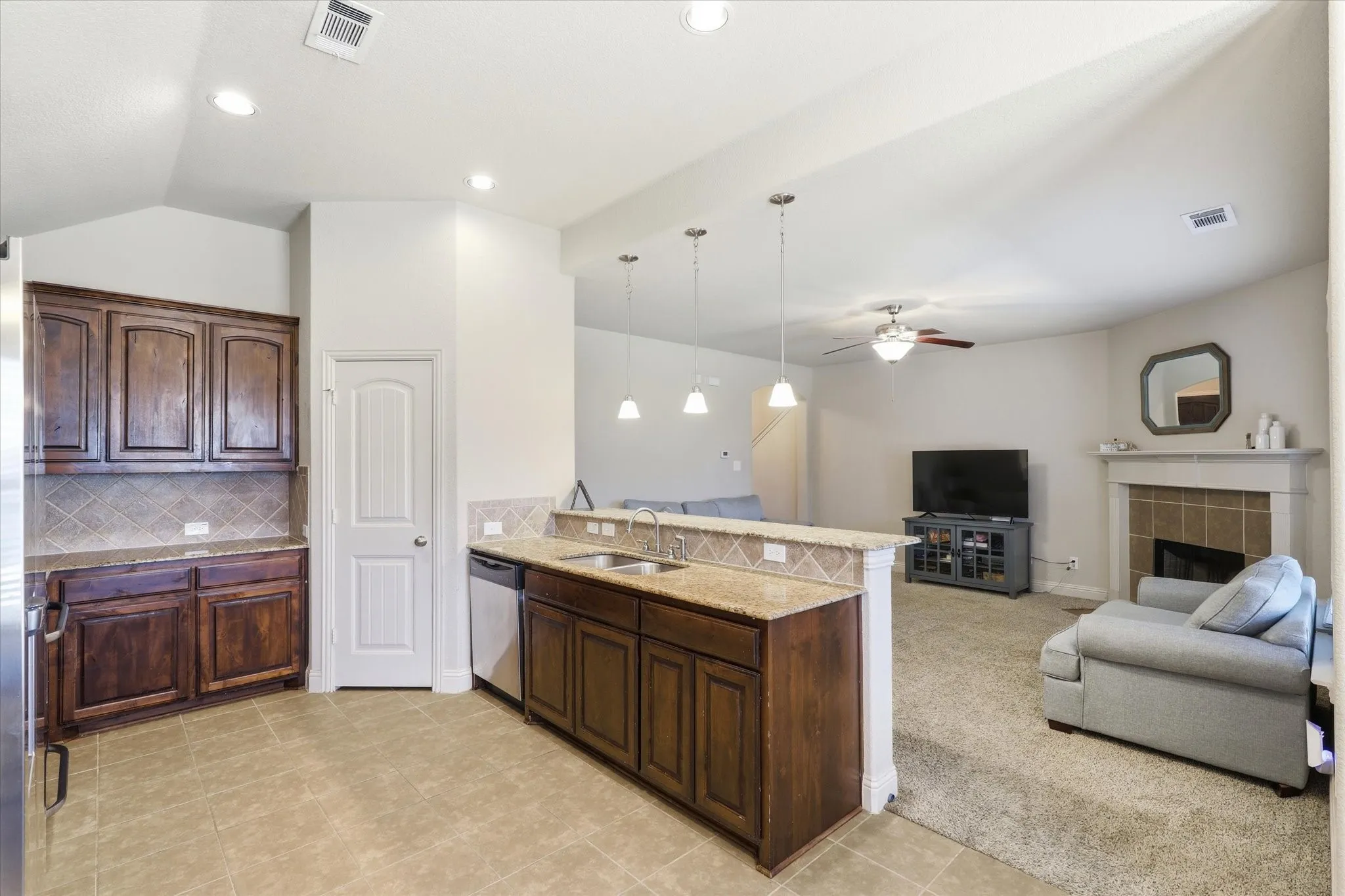 Kitchen with dark wood cabinetry, granite countertops, and tile backsplash