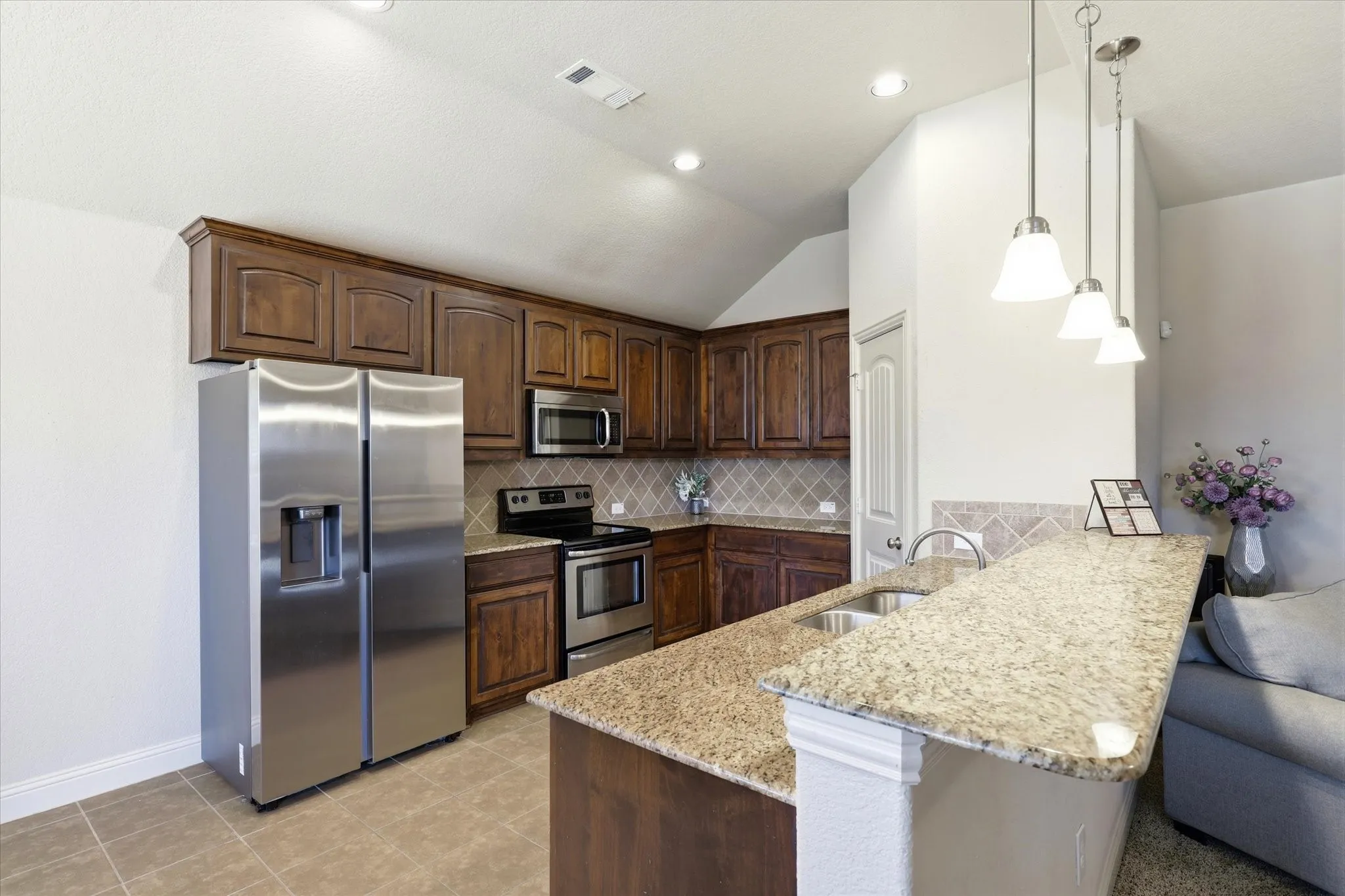 Kitchen featuring a stainless steel appliance package, granite countertops, tile backsplash, wood cabinetry, and recessed lighting