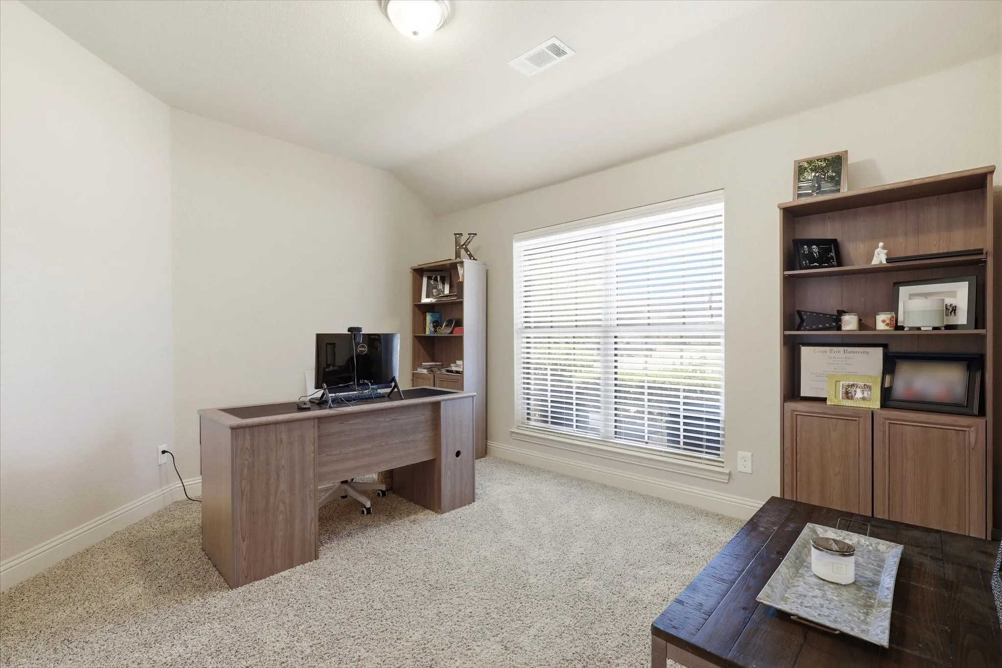 Carpeted room featuring a window with blinds, a built-in bookshelf, and recessed lighting