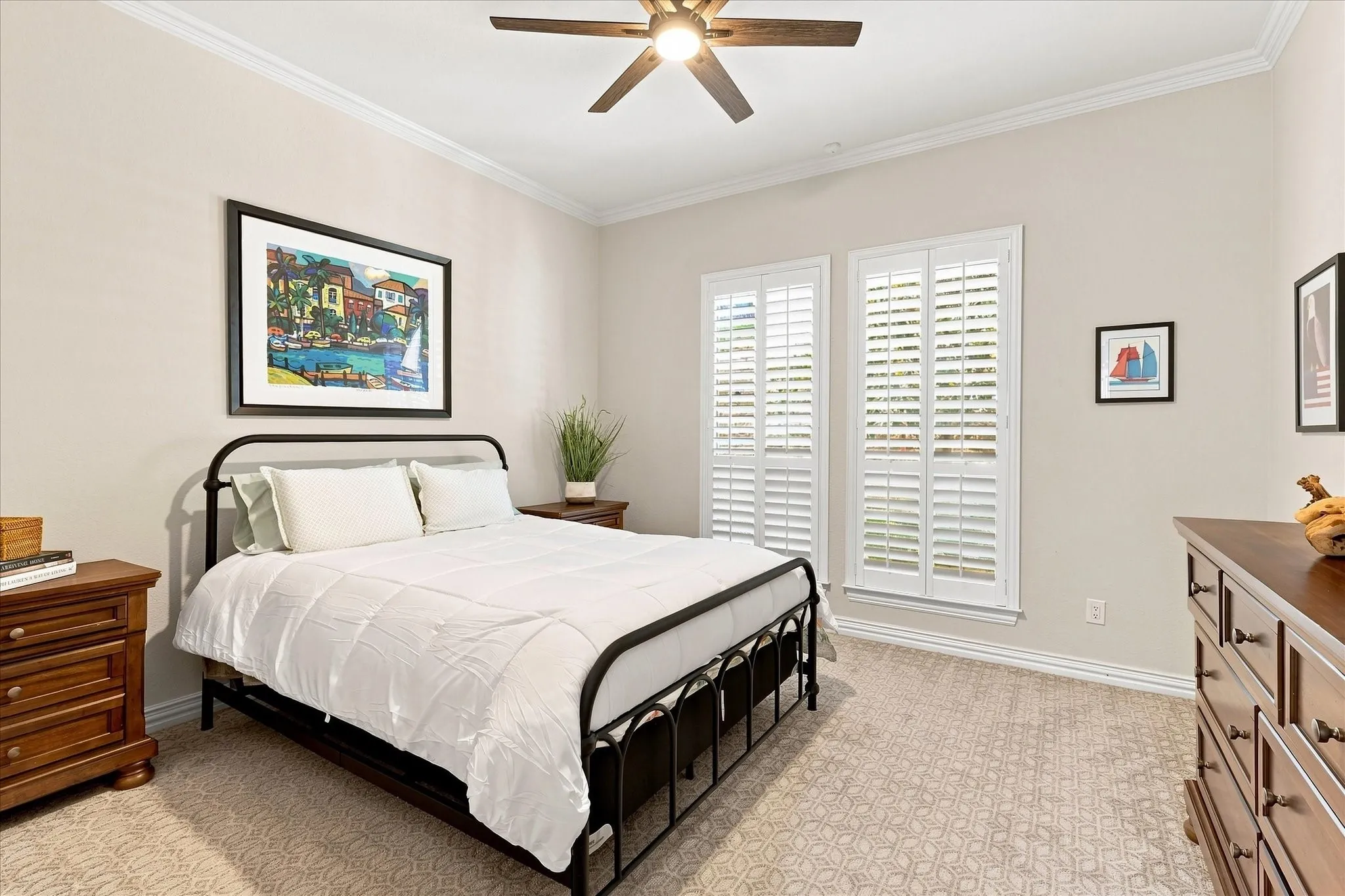 Recessed ceiling with crown molding, ceiling fan, neutral wall paint, two windows with plantation shutters, and patterned carpeting