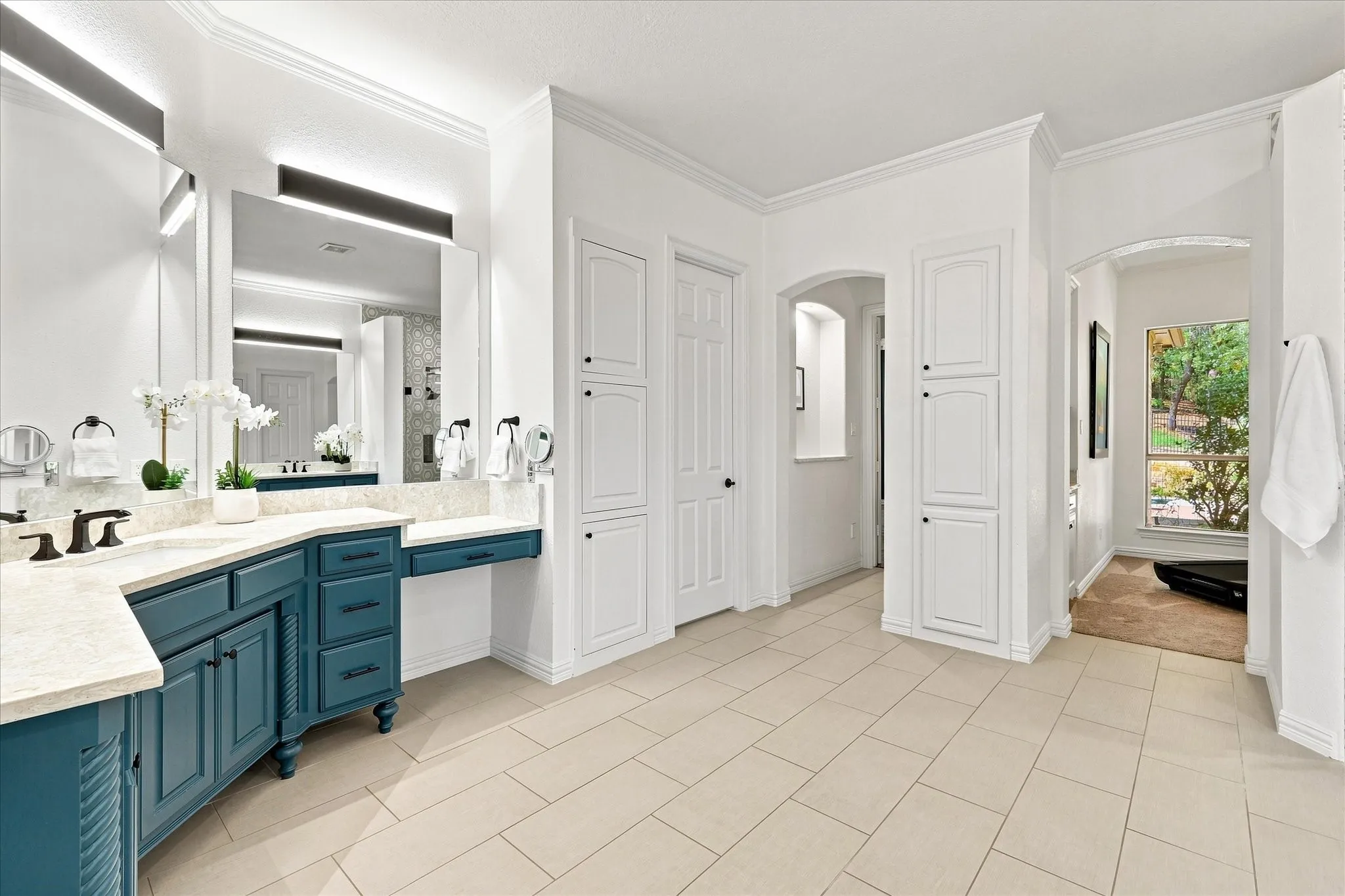 Dual vanities with stone countertops, built-in cabinetry, tiled flooring, and arched doorways