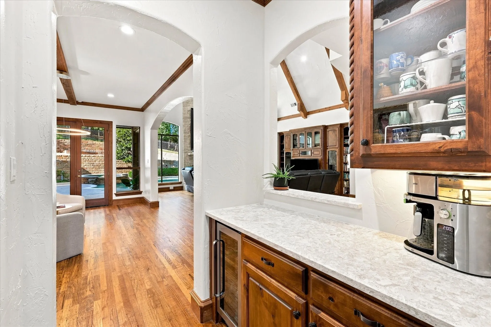 Built-in cabinetry with glass-front display, undermount lighting, and stone-finish countertop