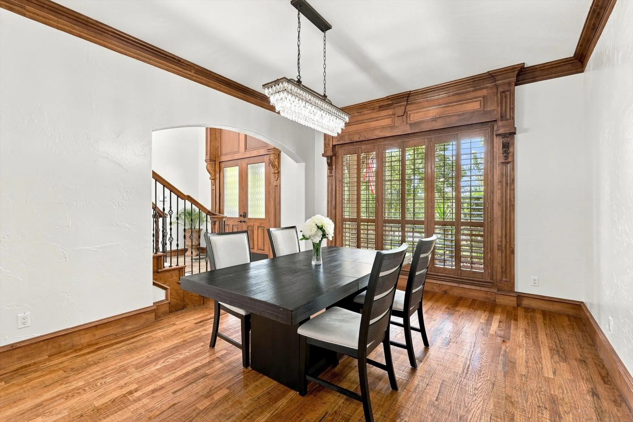 Wood-finish flooring, white walls, and a crystal chandelier