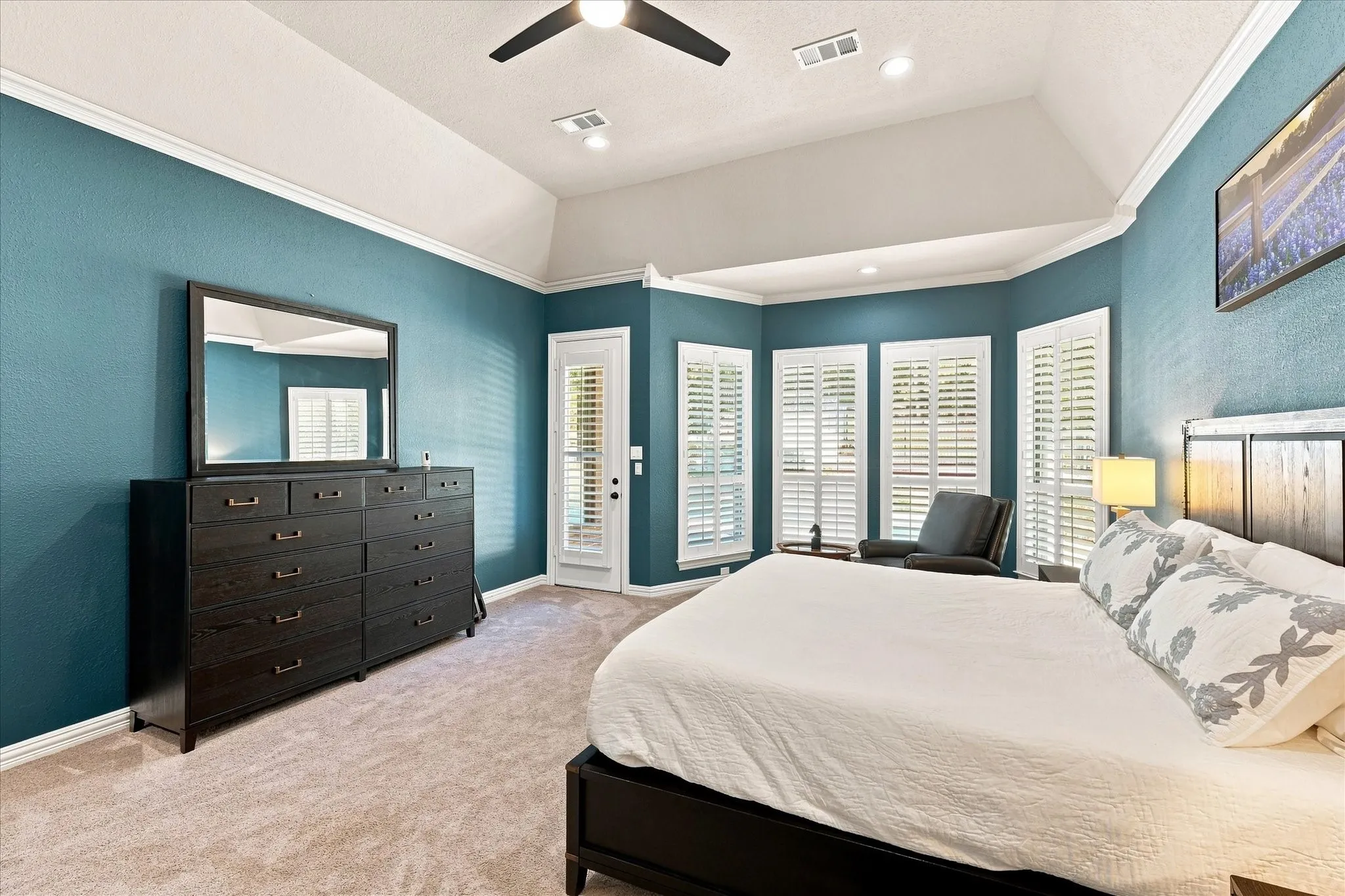 Vaulted ceilings, a ceiling fan, and recessed lighting enhance this carpeted room