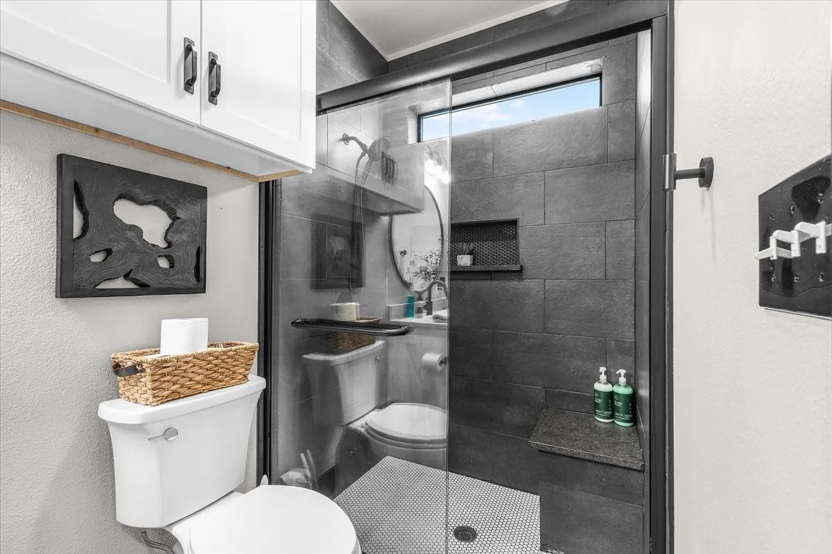 Glass-enclosed shower with dark tile surround, built-in shower niche, and integrated shower​​‌​​​​‌​​‌‌​‌‌​​​‌‌​‌​‌​‌​​​‌​​ bench