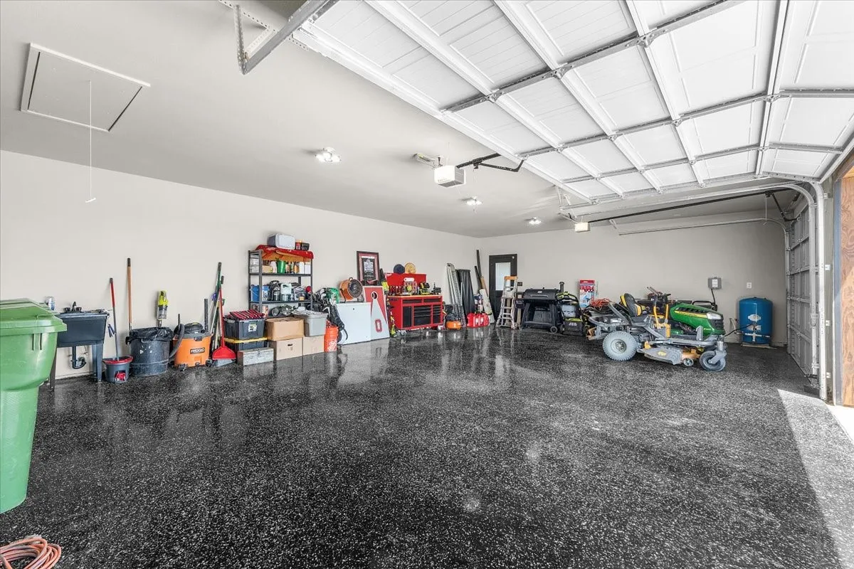 Expansive garage featuring a high overhead door, durable speckled flooring, and a utility sink