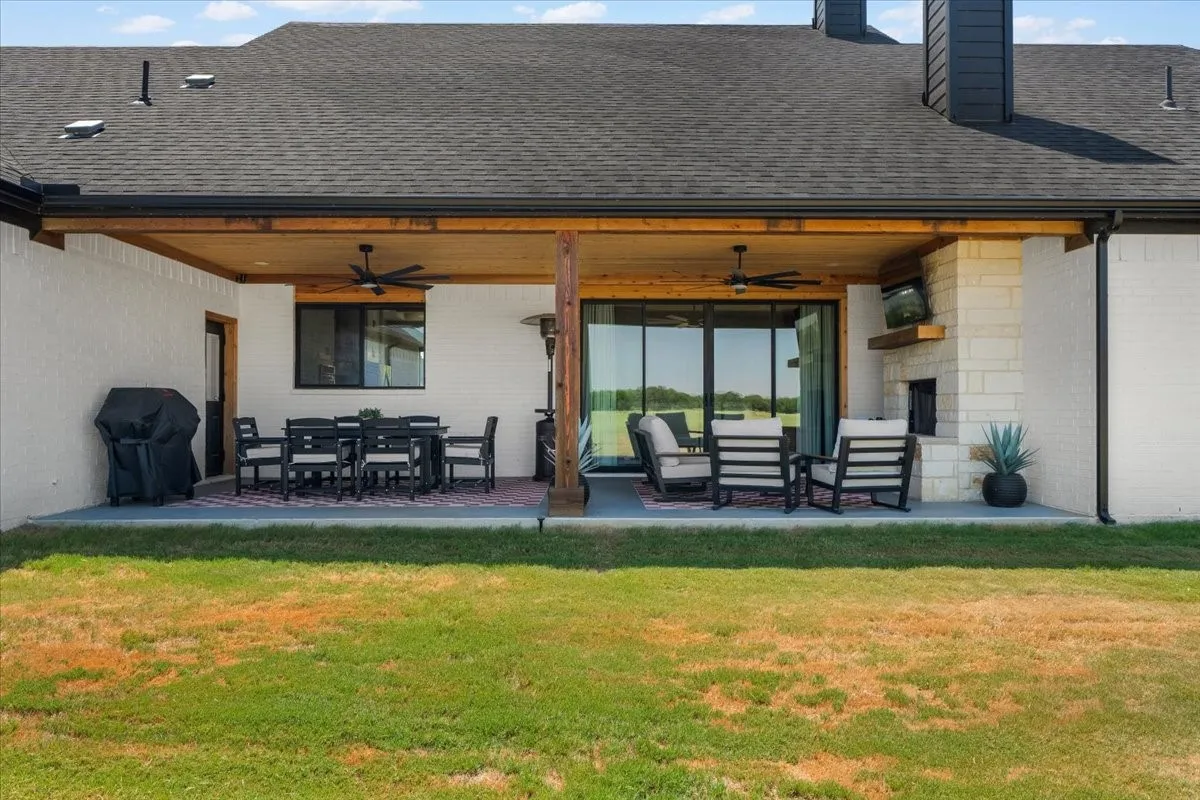 Covered patio featuring a ceiling fan, stone fireplace, and expansive sliding glass doors