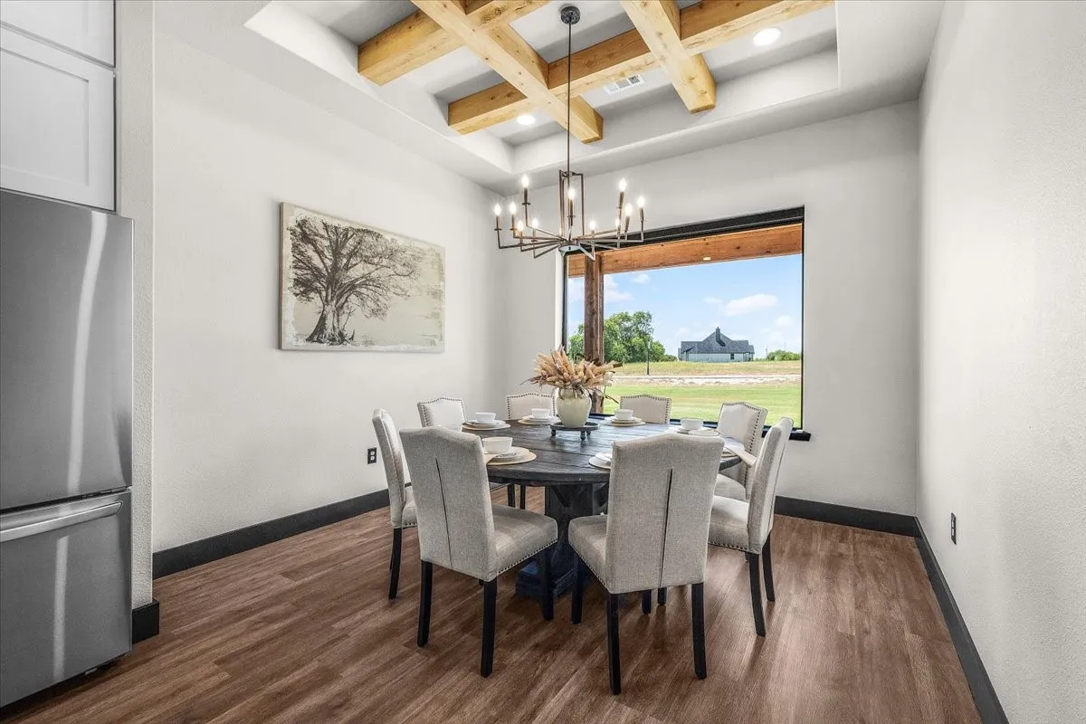 Tray ceiling with exposed wood beams, wood-finish flooring, large window with black trim, and a modern chandelier