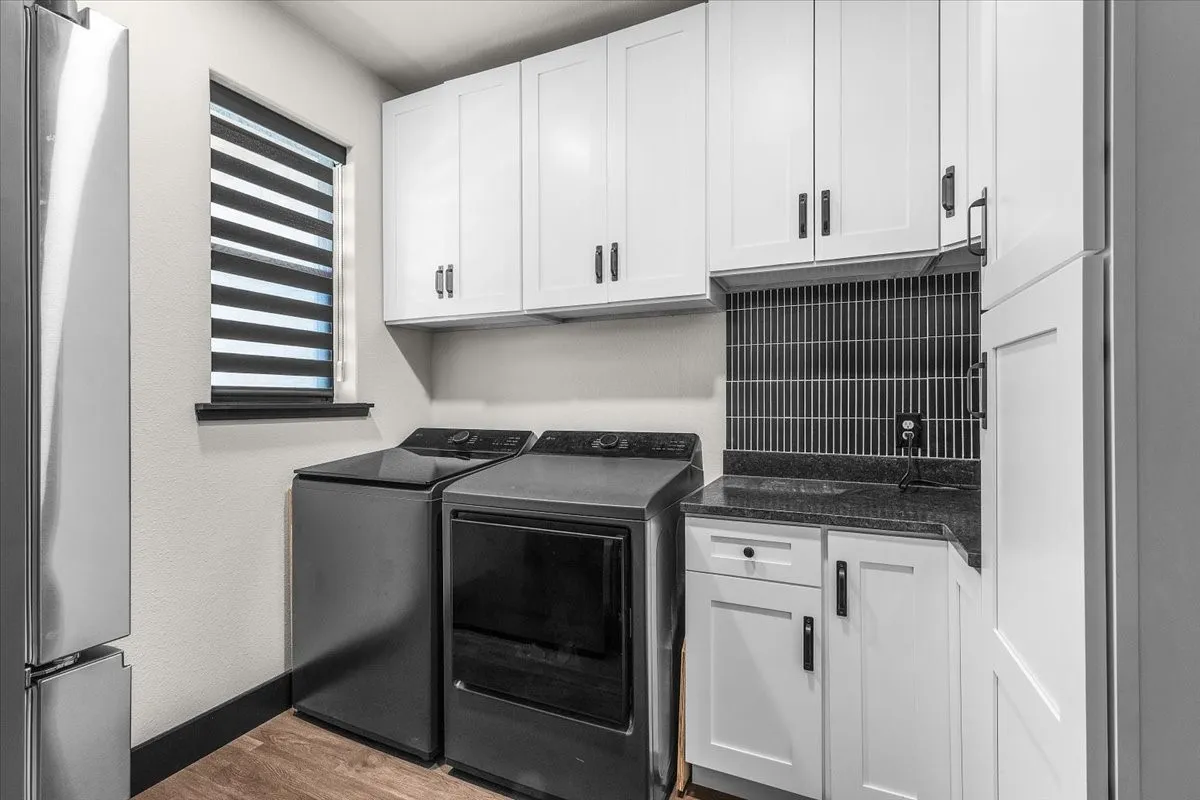 White shaker cabinetry with matte black hardware, dark tile backsplash, and dark countertop with an integrated sink