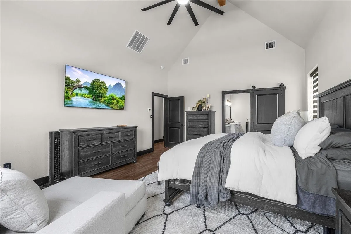 Vaulted ceiling with a ceiling fan, recessed lighting, wood-finish flooring, and a sliding barn door