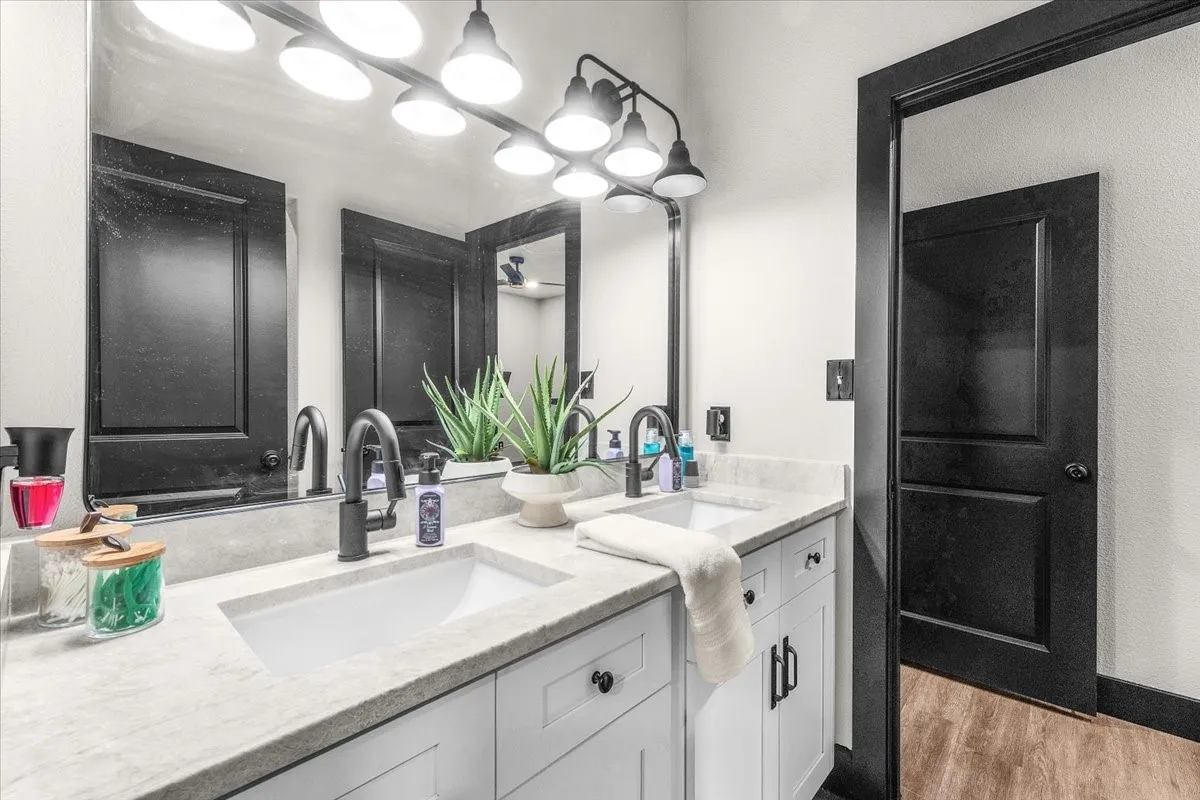 Dual rectangular undermount sinks set in a light-toned countertop, accompanied by matte black gooseneck faucets