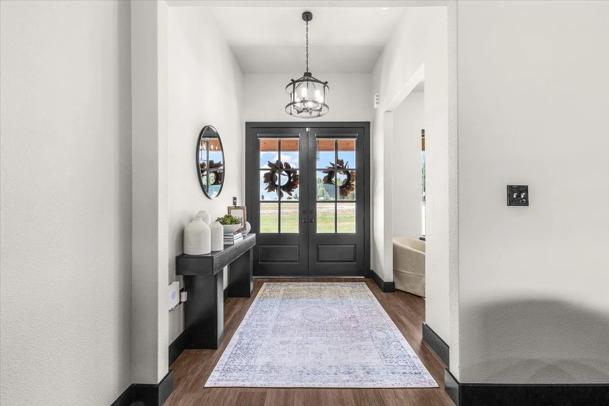 Double entry doors with glass panels, wood-finish flooring, and a decorative pendant light fixture