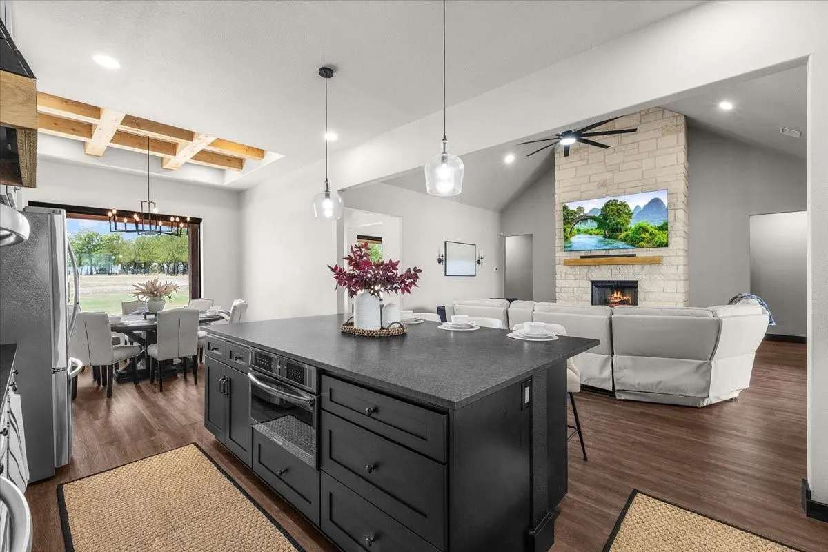 Open-concept layout with wood-finish flooring, a kitchen island featuring an integrated microwave, and pendant lighting