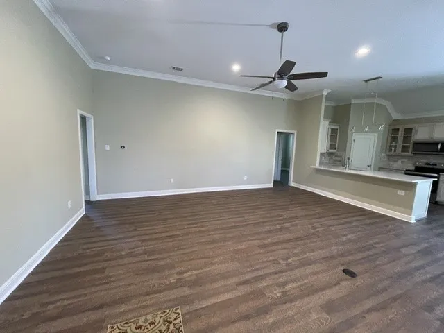 Spacious room featuring wood-finish flooring, crown molding, a ceiling fan, and recessed lighting