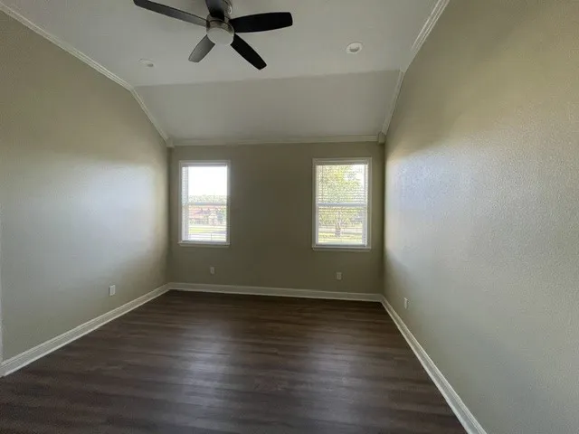 Vaulted ceiling with crown molding, ceiling fan, recessed lighting, wood-finish flooring, and two windows