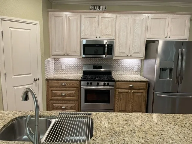 Stainless steel appliances, granite countertops, tile backsplash, built-in microwave, and under-cabinet lighting