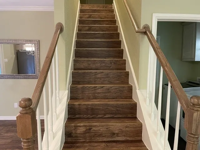Staircase featuring wood-finish treads and risers, white balusters, and a wood-finish handrail