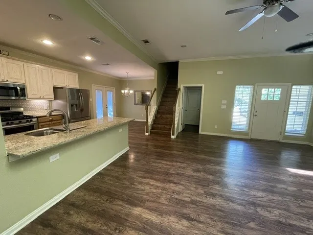 Wood-finish flooring throughout, kitchen with light-toned cabinetry, stainless steel appliances, and a breakfast bar