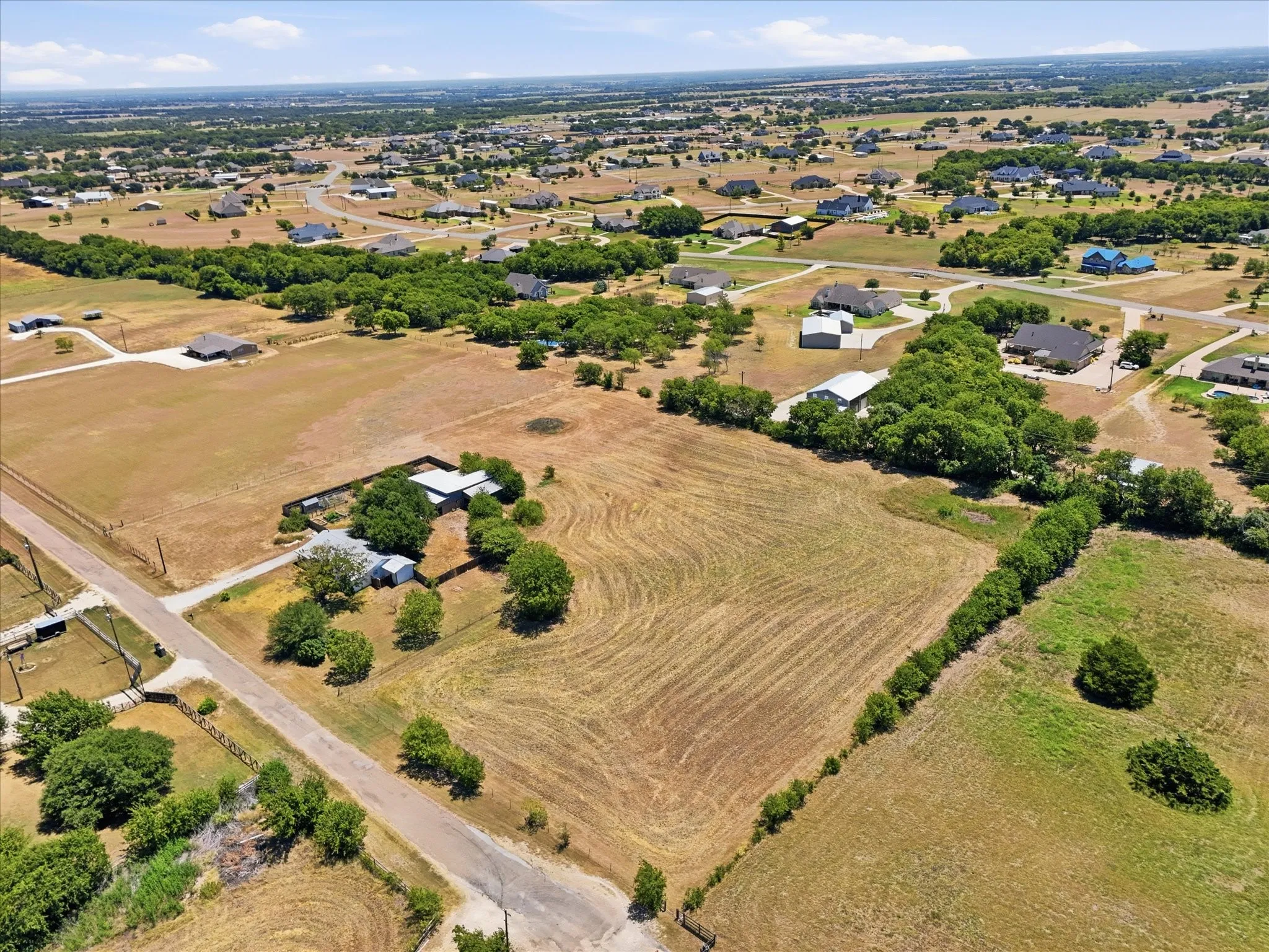 Expansive land parcel with surrounding residential properties, established roads, and scattered mature trees