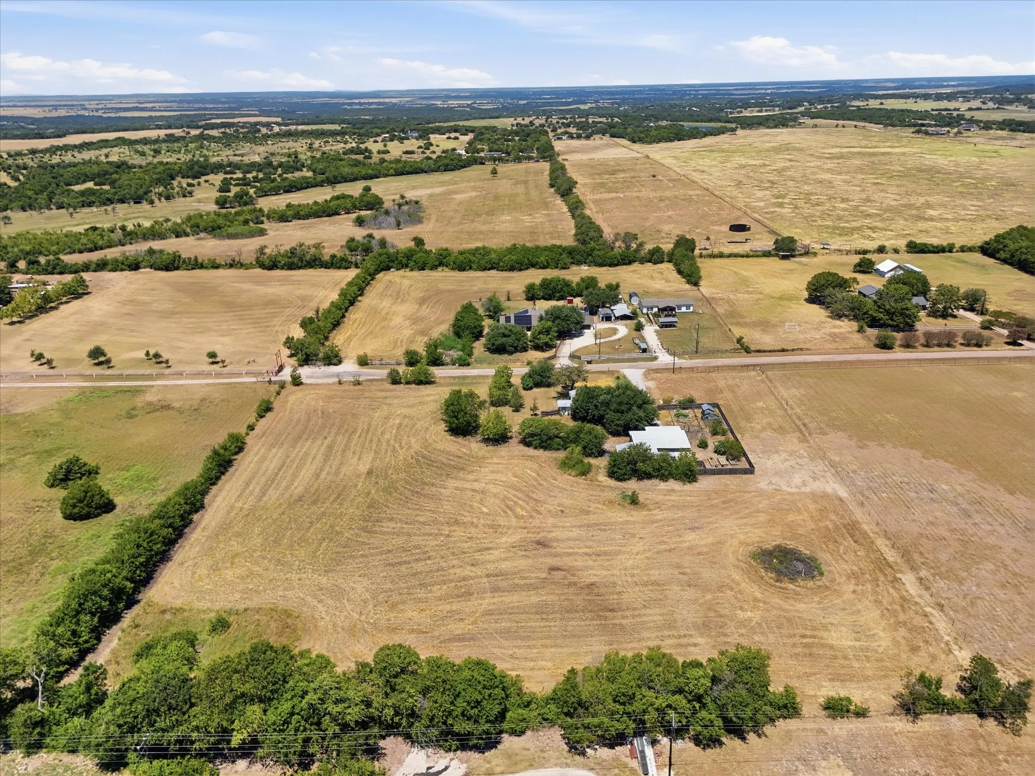 Expansive rural landscape featuring multiple parcels of land, established tree lines, and a visible pond