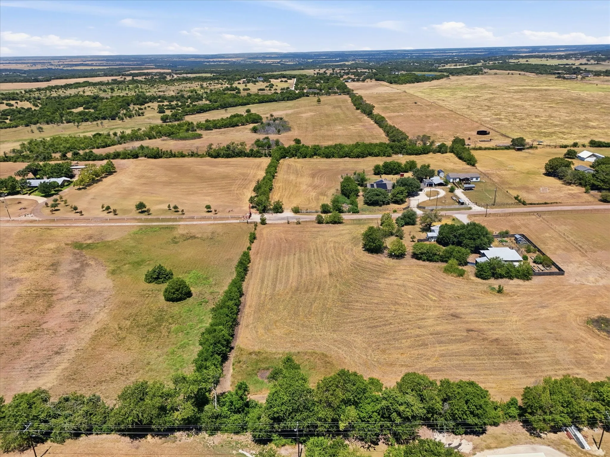 Expansive rural property featuring multiple cleared land parcels and scattered mature trees